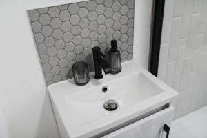 a bathroom sink with two bottles and glasses on it at Garmoyle Road Flat 2 in Liverpool