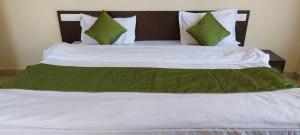 Cama grande con sábanas y almohadas verdes y blancas en Mountain Villa Mcleodganj, en Kangra