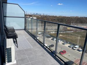 een balkon met een stoel en uitzicht op een parkeerplaats bij Apartament Vulcano Komfort Nowy Ursus in Warschau
