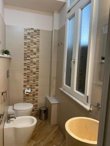 uma casa de banho com um lavatório, um WC e uma janela. em A 4 PASSI em Reggio di Calabria