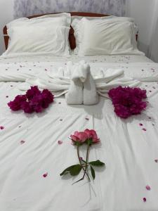 a bed with pink flowers and a stuffed animal on it at The Dream Inn in Ella