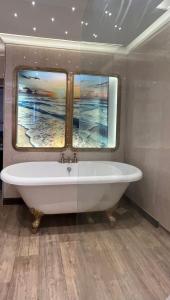 a bath tub in a bathroom with a window at Captain's Nook, Luxurious Victorian Apartment with Four Poster Bed and Private Parking only 8 minutes walk to the Historic Harbour in Brixham