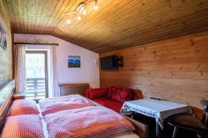1 dormitorio con 1 cama y 1 sofá rojo en Mittereggalm, en Mühlbach am Hochkönig