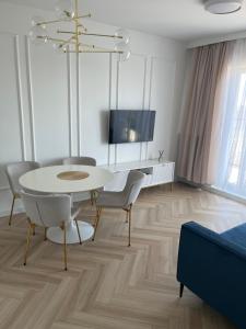 a living room with a table and chairs and a tv at Apartament Vulcano Komfort Nowy Ursus in Warsaw
