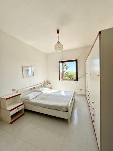 een witte slaapkamer met een bed en een raam bij Trilocale con cortile - Lu Fraili in Budoni