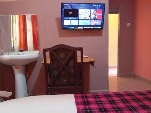 Quanam Woods Hotel في لودوار: غرفة نوم مع حوض وتلفزيون على الحائط