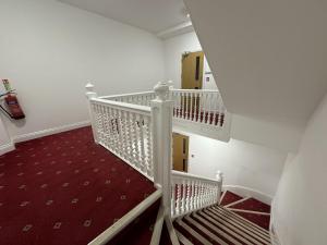 una escalera ascendente con alfombra roja en una habitación en Gorgeous Spacious Apartment with Sea View, en Walton-on-the-Naze