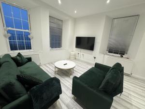 Gorgeous Spacious Apartment with Sea View في ولتون - أون - ذى - ناز: غرفة معيشة مع أريكة خضراء وطاولة