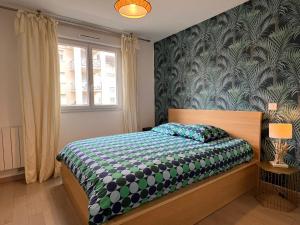 - une chambre dotée d'un lit avec un couvre-lit vert et blanc dans l'établissement location 3 chambres spacieuses dans appartment 2 mn RER Bussy Saint georges, à Bussy-Saint-Georges