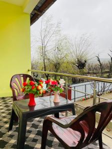 een tafel met 2 stoelen en bloemen op een balkon bij Fab Ocean Guest House in Tangmarg