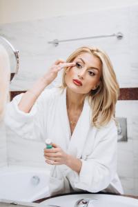 a woman brushing her teeth in front of a bathroom mirror at Hotel Novera in Timişoara