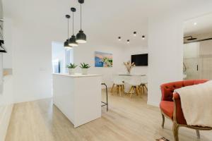 uma cozinha e sala de estar com paredes brancas e uma cadeira vermelha em Ca nAntonia em Lloseta