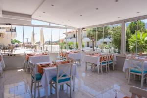 un restaurante con mesas y sillas blancas y ventanas en LESLION HOTEL TURUNC en Marmaris
