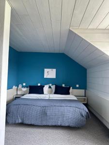 ein Schlafzimmer mit einer blauen Wand und einem Bett in der Unterkunft „gg“ games garni Hotel Säntis in Teufen