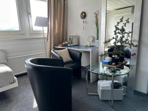 ein Wohnzimmer mit 2 Stühlen und einem Glastisch in der Unterkunft „gg“ games garni Hotel Säntis in Teufen