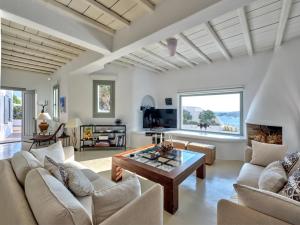 sala de estar con muebles blancos y ventana grande en Cordelia Villa en Psarou