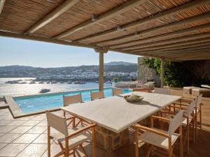 une terrasse avec une table, des chaises et une piscine dans l'établissement Cordelia Villa, à Psarrou