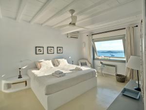 Dormitorio blanco con cama y ventana grande en Cordelia Villa en Psarou