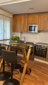 Una cocina con mesa y sillas y un microondas. en APARTAMENTO TURÍSTICO SAN NICOLAS, en Avilés