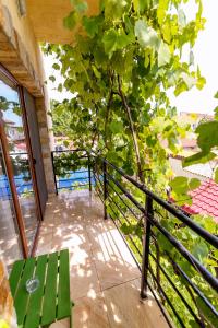 a green bench sitting on a balcony next to a tree at Casa Amelie Mangalia in Mangalia