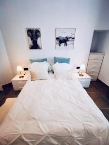 1 dormitorio con 1 cama blanca grande y 2 mesitas de noche en Apartamento en C/ León y Castillo (C/ Real) Centro de Arrecife, en Arrecife