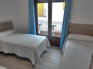 1 dormitorio con 2 camas y ventana con balcón en Hostal Casa Fermina- A 2 horas de las pistas de esquí, en Trevélez