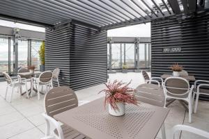 a patio with white tables and chairs and windows at Apartamenty Towarowa Poznań in Poznań