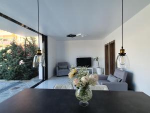 uma sala de estar com um vaso de flores sobre uma mesa em One Bedroom Pool House by Olivujoj em Anavissos