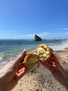 a person holding a partially eaten doughnut on the beach at Casa Vacanza Nonna Maria in Torre Pali 