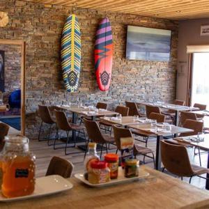 a restaurant with tables and surfboards on the wall at Bio-Motel in Saint-Vulbas