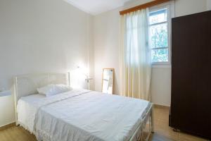 a bedroom with a white bed and a window at Elena’s House Sivota Lefkadas in Sivota