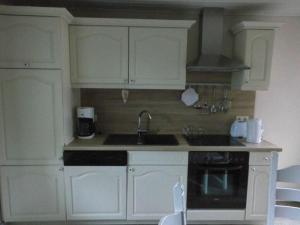 a kitchen with white cabinets and a sink and a stove at Dollhouse Modern retreat in Wiesmoor