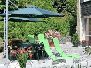 un grupo de sillas verdes y una sombrilla en un patio en Saaleland Apartment 3 en Schleiz