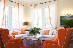 un soggiorno con sedie arancioni e un divano bianco di Villa Liberty al mare a Marina di Massa