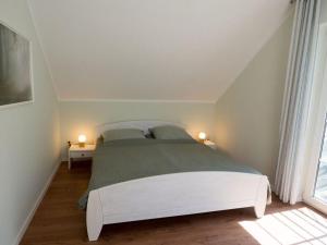 a bedroom with a large white bed with two lamps at Pure nature, modern retreat in Lenz