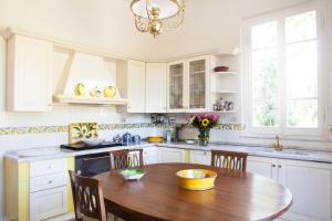 a white kitchen with a wooden table and chairs at Villa Liberty al mare in Marina di Massa