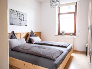 a bedroom with a bed with a wooden frame and a window at Spitzhausblick in Haus Felix in Radebeul