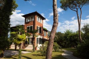 una grande casa in mattoni con un albero di fronte di Villa Liberty al mare a Marina di Massa