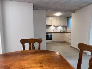 uma cozinha com uma mesa de madeira e cadeiras num quarto em La Vigneronne, Lake view em Arlesheim