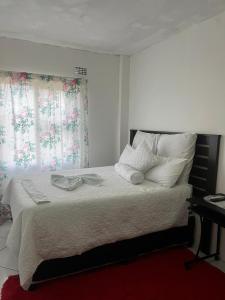 a bedroom with a bed with white sheets and pillows at Sunset Guesthouse - Mthatha in Mthatha
