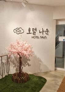 a tree with pink flowers in front of a wall at Gunsan Hotel Naun in Gunsan