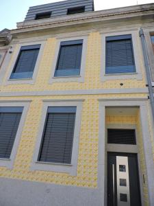 a yellow building with four windows and a door at RS Porto Campanha in Porto