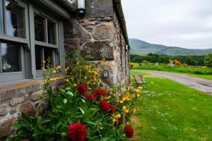 una casa de piedra con un jardín de flores junto a una ventana en Colmeallie Bothy - Seasgair Lodges en Brechin
