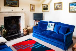 sala de estar con sofá azul y chimenea en Colmeallie Bothy - Seasgair Lodges en Brechin