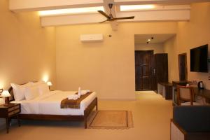 1 dormitorio con 1 cama y ventilador de techo en KASHI ANANDAM SPIRITUAL & WELLNESS VEDIC VILLAGE LLP en Kakarmatha