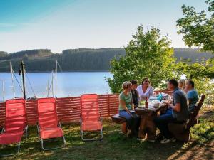 Un groupe de personnes assises à une table au bord d'un lac dans l'établissement Saaleland Apartment 1, à Schleiz