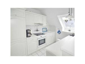 uma cozinha branca com um lavatório e um fogão em Maisonnette with charm em Scharbeutz