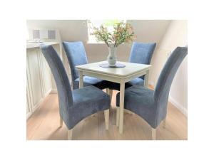 uma mesa com cadeiras azuis e um vaso com flores em Maisonnette with charm em Scharbeutz