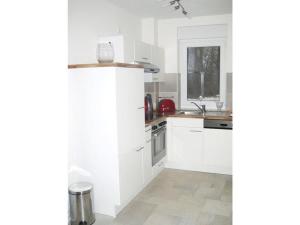a white kitchen with white cabinets and a sink at Apartment Del Rose in Wilhelmshorst