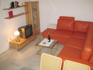 a living room with a red couch and a tv at Apartment Del Rose in Wilhelmshorst